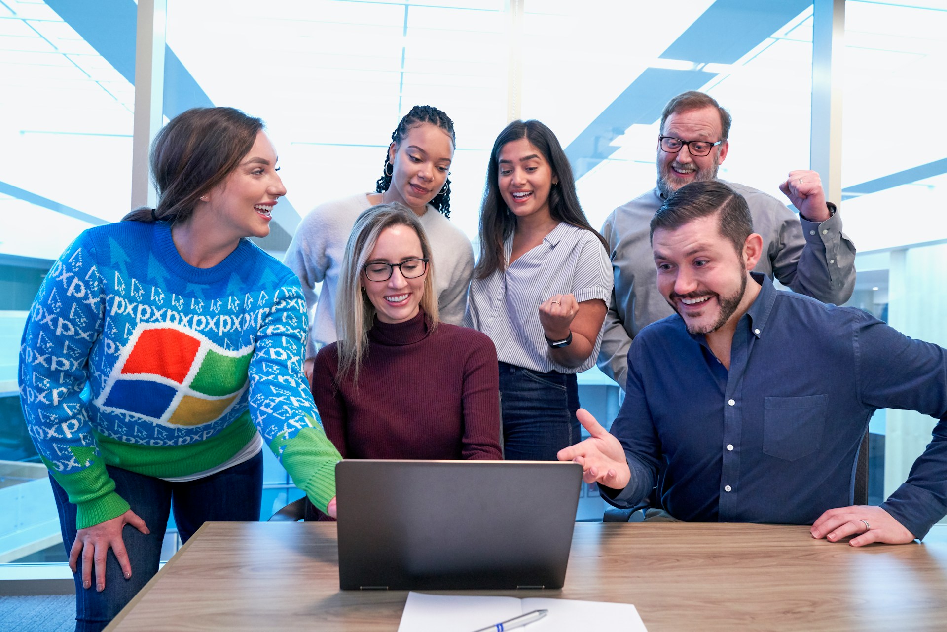 Maroon Sweater Woman Laptop with many people sitting for team coaching