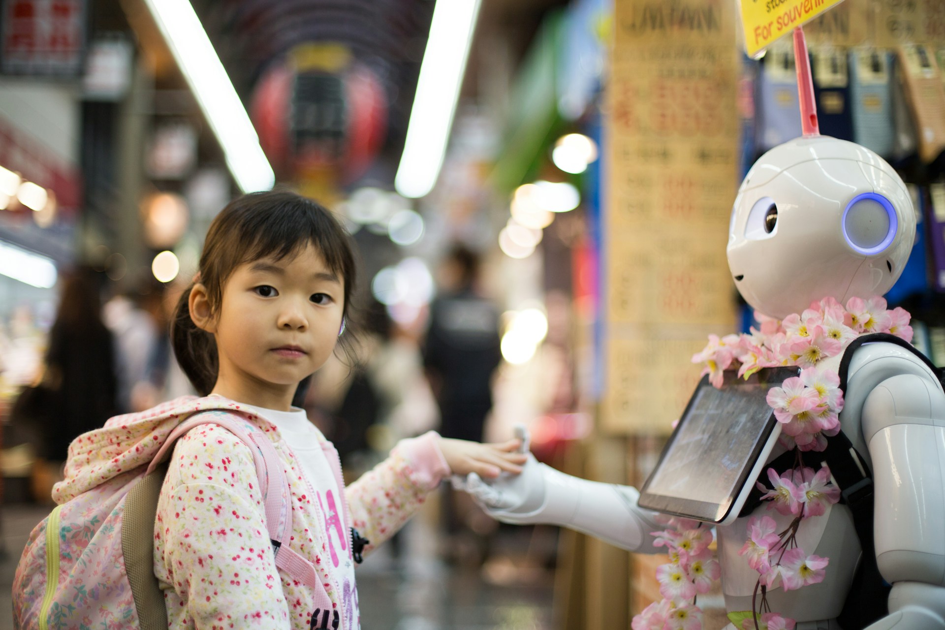 Ethical AI coaching framework, Young girl holding the hand of a robot.